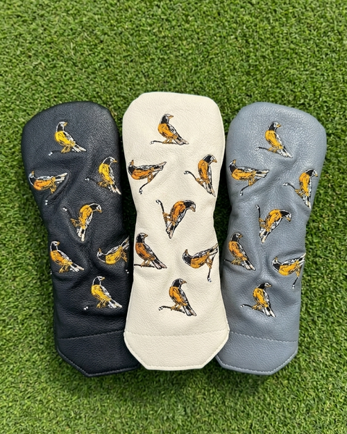 Three golf club heads with bird patterned covers on a grass background