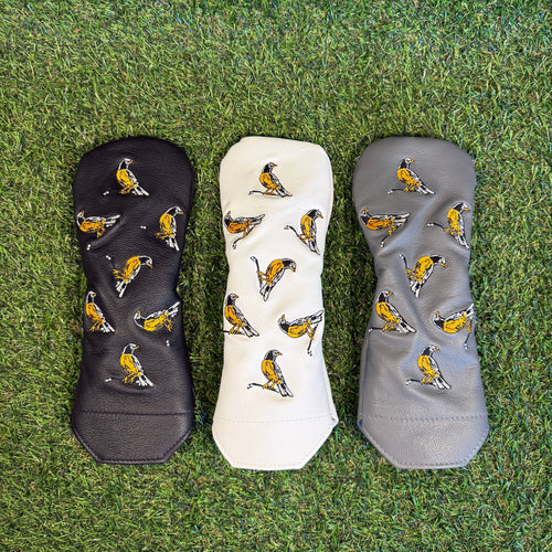 Three golf club covers with bird pattern on grass